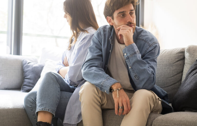 Paar sitzt schweigend nebeneinander auf dem Sofa