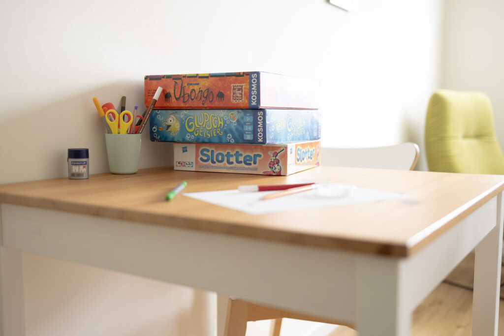 Tisch mit Gesellschaftsspielen, Stiften und Papier im Kinder- und Jugendlichenbereich